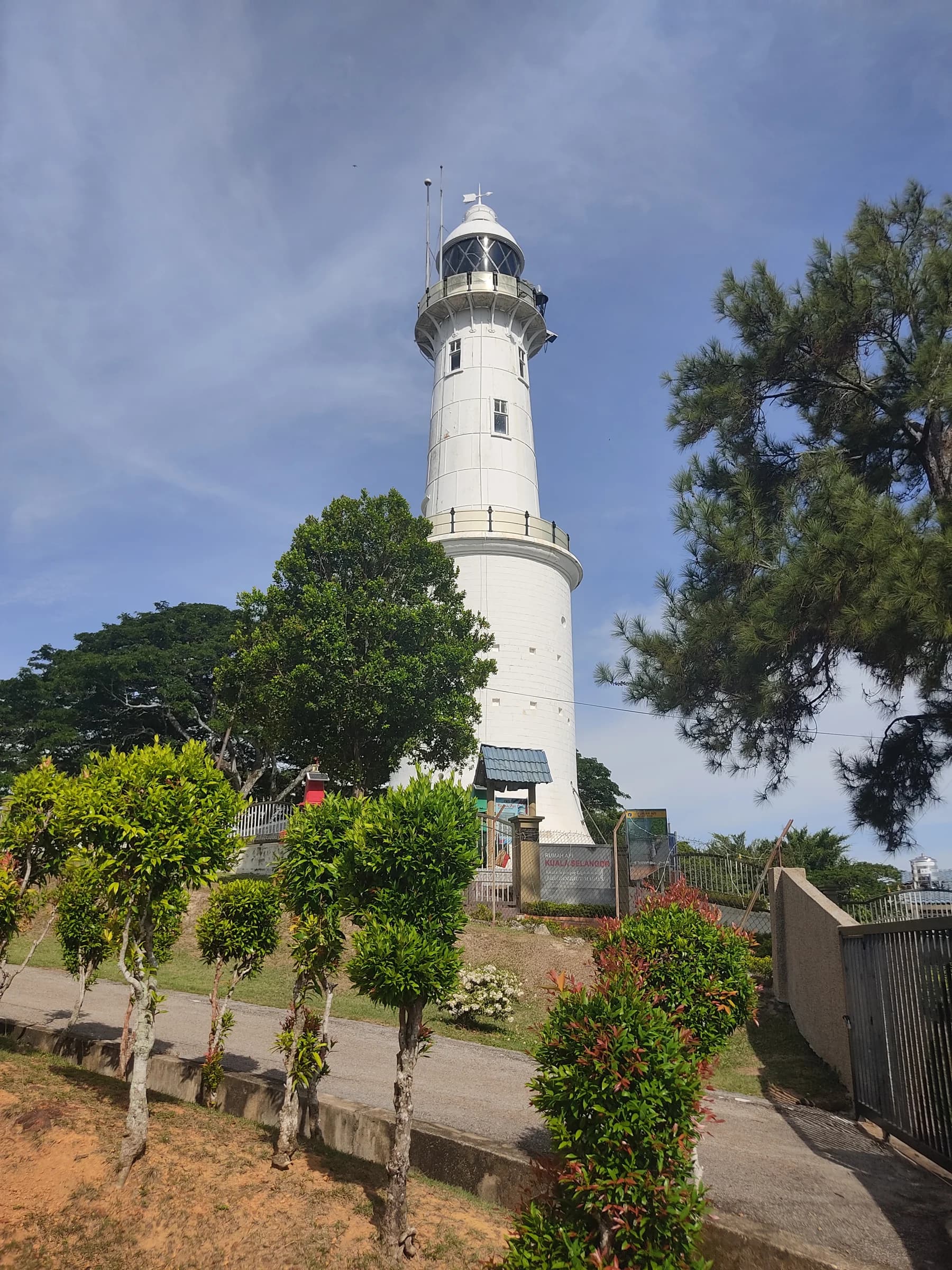 White Kuala Selangor lighthouse at Bukit Melawati among trees, photographed by ZKang123 in June 2022