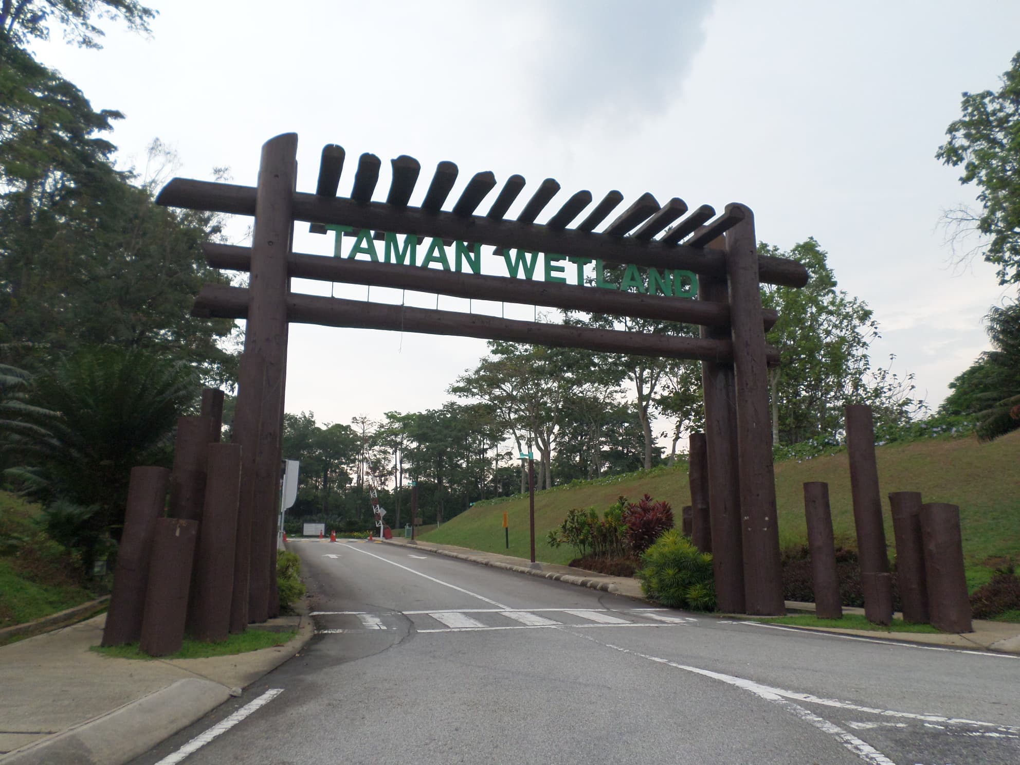 Taman Wetland entrance sign and tree-lined road in Putrajaya, photographed in November 2015